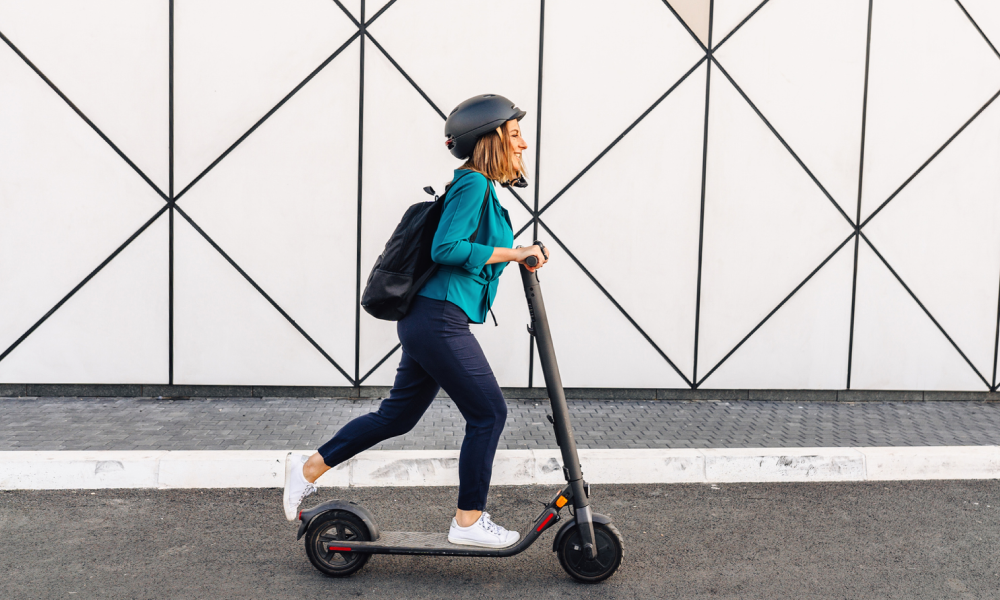 Foto van een vrouw van middelbare leeftijd die op een elektrische scooter naar haar werk rijdt.
